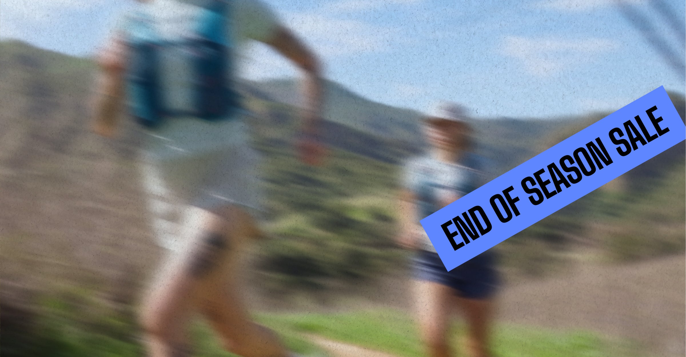 Three trail runners are seen from behind running on a dirt path through tall grass, wearing NATHAN hydration packs and athletic clothing.