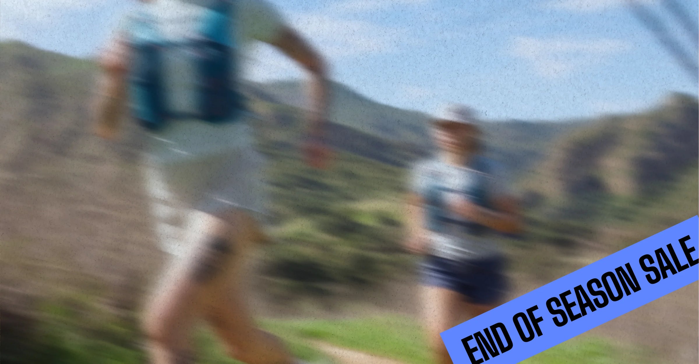 Three trail runners are seen from behind running on a dirt path through tall grass, wearing NATHAN hydration packs and athletic clothing.